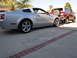 2006 Ford Mustang - A silver coupe is parked next to a red SUV. The coupe appears to be a Ford Mustang.
