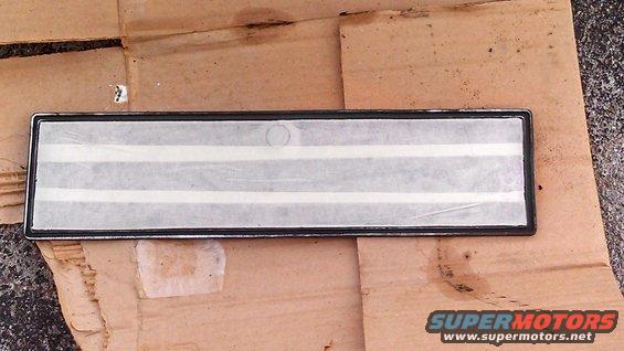 Rectangular chrome trim piece with white stripes on a piece of cardboard
