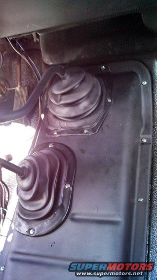 Interior shot of two rubber shifter boots on a vehicle floor. One is larger than the other
