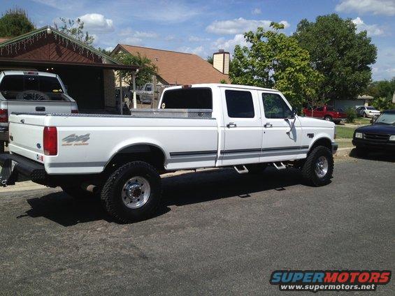 White 1997 Ford F-350 crew cab pickup truck with 4x4 badging, parked on asphalt