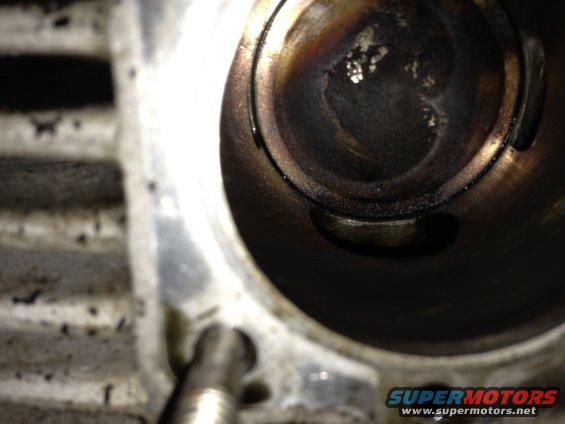 Close-up of an engine cylinder with carbon buildup. Watermark says SUPERMOTORS