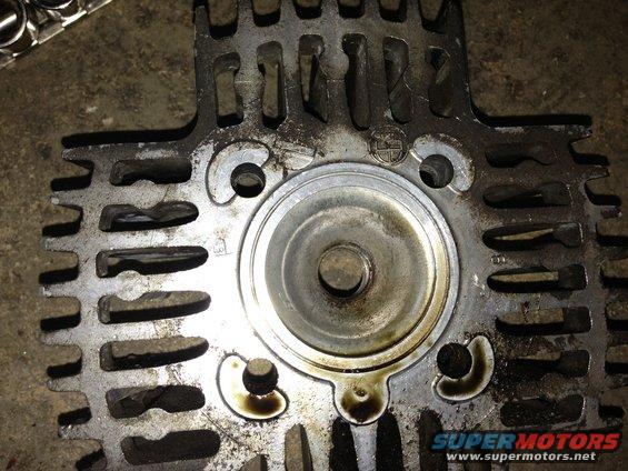 Close-up of a dirty, cast metal engine cylinder head with cooling fins