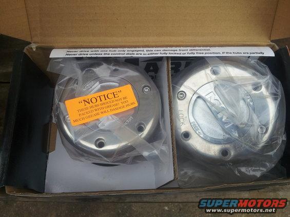 Two new manual locking hubs in a cardboard box, one with an orange notice sticker