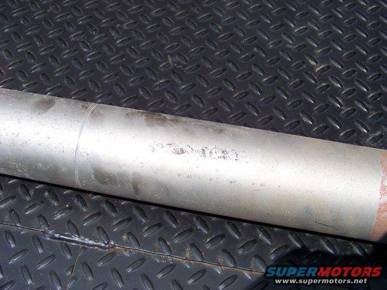 exhaust pipe with some faded markings on it, resting on a diamond plate surface