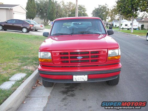 Red Ford F-150 parked on street, front view. License plate reads 3LGT943