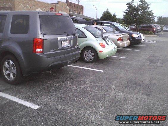 Parked cars including a gray SUV, a light green Volkswagen Beetle with a spoiler, and a silver sedan