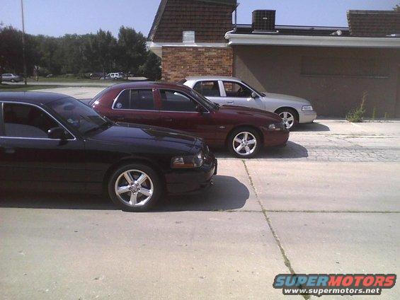 Three Ford Crown Victorias parked side-by-side, black, maroon, and silver