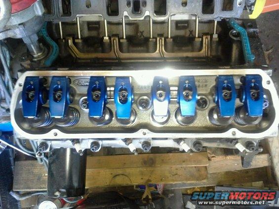 Close-up of engine valve train with blue roller rockers and valve springs