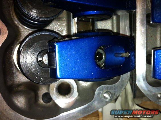 Close-up of blue roller rocker arm and valve spring assembly in an engine
