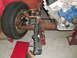 1964 Ford Fairlane - Close-up view of engine and suspension components, including a tire and brake assembly, on a vehicle undergoing work.