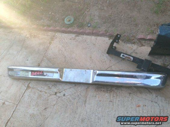 Chrome bumper with a red and white 'DARE' sticker on it, lying on concrete