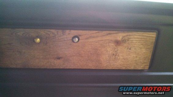 Wood grain trim panel with two knobs, one gold and one silver