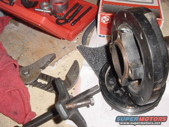 Automotive crankshaft pulley and puller tool on a workbench with a red toolbox and KD brand box