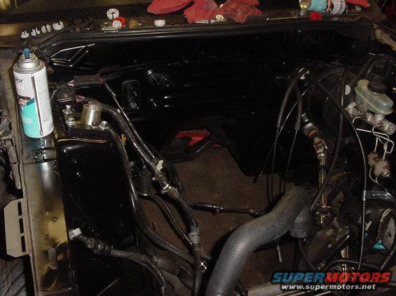 Engine bay with spray can and various hoses and wires. Some parts appear to be painted black
