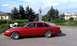 1992 Ford Crown Victoria - A red 1992 Ford Crown Victoria sedan is parked outdoors near a statue and trees.