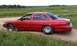 1992 Ford Crown Victoria - A red 1992 Ford Crown Victoria is parked on a dirt road in a grassy field.