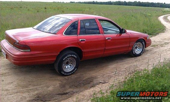 Red 1992 Ford Crown Victoria sedan parked on a dirt road, side view