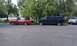 1992 Ford Crown Victoria - A red sedan, a blue pickup truck, and a silver SUV are parked on a street next to trees.
