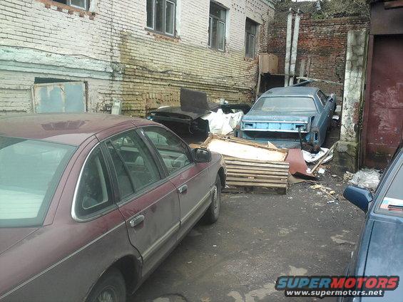 Maroon 1992 Ford Crown Victoria side view parked in a yard with other car parts