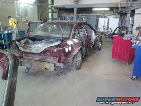 1992 Ford Crown Victoria in a workshop, undergoing repairs. Trunk is open and interior is partially disassembled