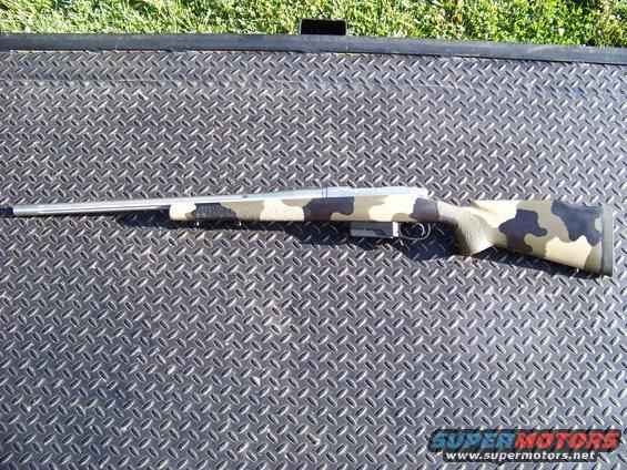 Camouflaged rifle with stainless steel barrel on a diamond plate surface