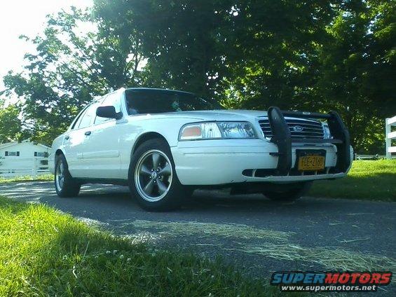 2004 Ford Crown Victoria with push bar and aftermarket wheels, parked on a driveway