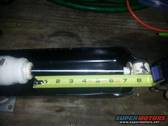 Shock absorber being measured with a tape measure showing approximately 8 inches