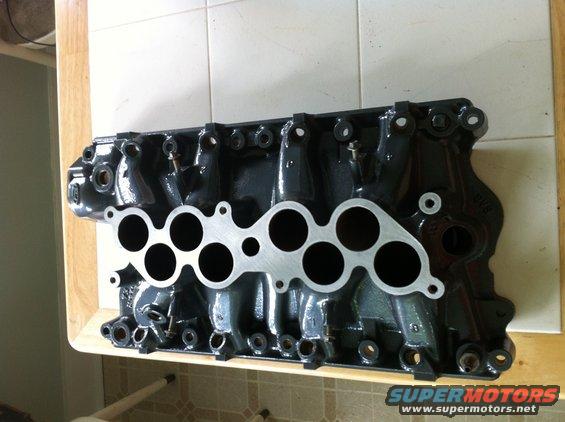 Black engine intake manifold with silver gasket surface