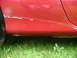 1993 Mazda MX-3 - Close-up of a red car's side panel showing damage and grass.