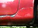 1993 Mazda MX-3 - Rust and paint damage visible on the lower section of a red car door.