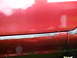 1993 Mazda MX-3 - The lower body panel of a red car shows signs of rust and damage.