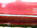 1993 Mazda MX-3 - Close-up of a red car's side skirt, showing signs of wear and corrosion.