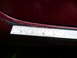 1993 Mazda MX-3 - A ruler is placed against the side skirt of a red car, measuring a gap.