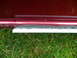 1993 Mazda MX-3 - The bottom edge of a car door shows wear and a white trim piece, with grass visible below.