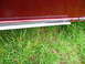 1993 Mazda MX-3 - Close-up of a car's side, showing the lower door panel and trim against a grassy background.