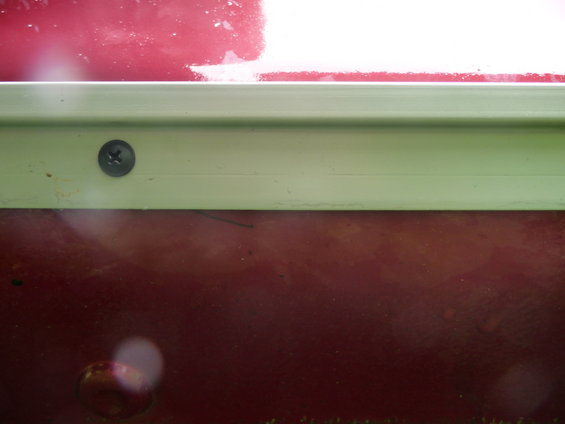 Side skirt detail with screw on red vehicle