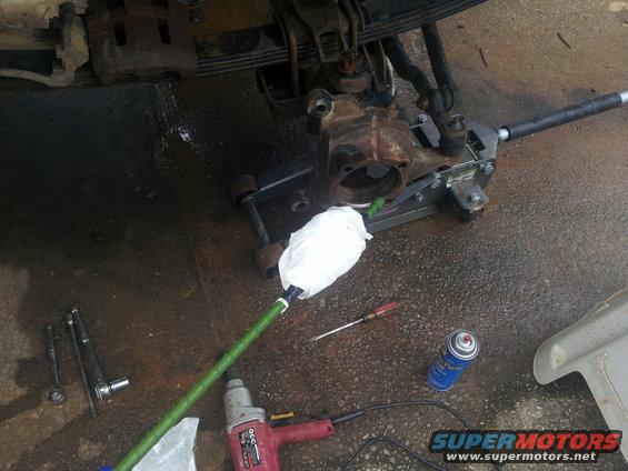 vehicle's front axle assembly on a jack with tools and spray can nearby