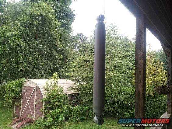 Shock absorber hanging from a wire, with a shed and trees in the background