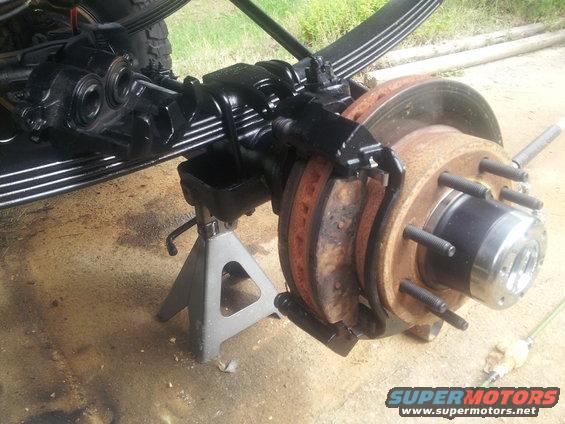 close-up of a vehicle's front axle with brake rotors and calipers, supported by jack stands