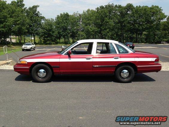 Red and white 2004 Ford Crown Victoria sedan, side view