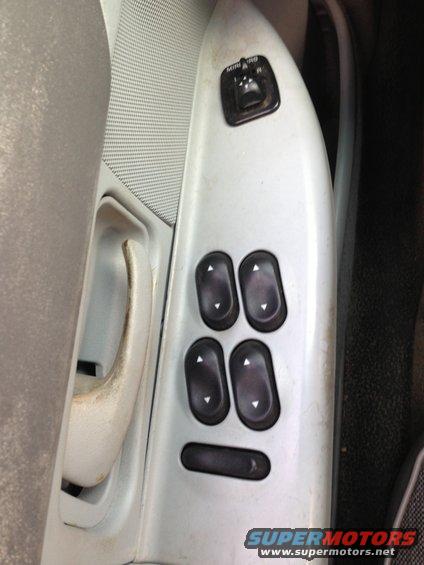 Interior door panel with power window and mirror controls. Includes four window buttons and a mirror adjustment switch