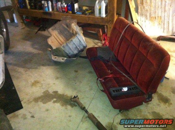 red velour bench seat and a metal part on garage floor