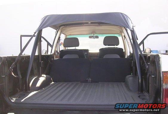 Back view of a pickup truck's interior, showing the bed, rear seats, and soft top