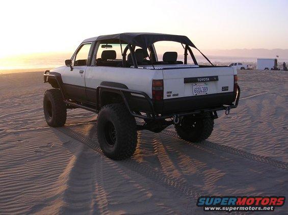 1983 Toyota pickup truck with soft top and off-road tires on a beach