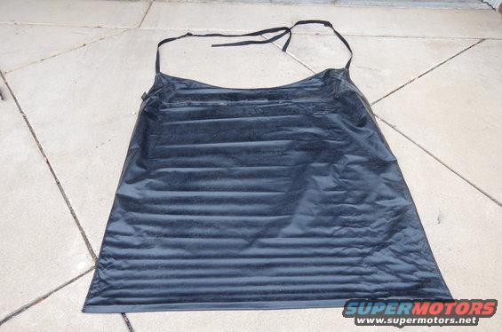 Black soft top with horizontal pleats and tie straps, laid flat on concrete