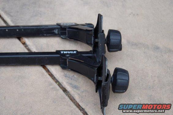 Two black Thule roof rack crossbars with mounting hardware visible