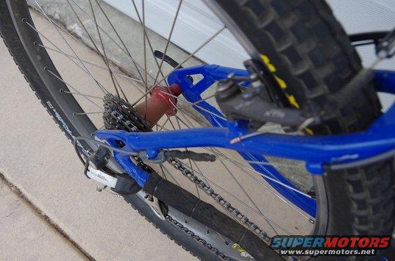 Blue bicycle frame with rear wheel, cassette, and derailleur visible