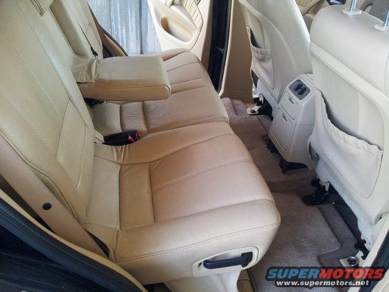 Back seats and floor of a car, showing tan leather upholstery and carpet