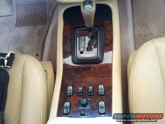 Tan leather seats flank a wood-trimmed center console with a gear shifter and multiple window controls in a 2000 Mercedes-Benz ML-Class