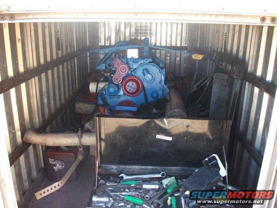 Blue engine and toolbox with tools inside a corrugated metal storage unit